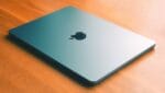 MacBook Air coloris minuit fermé posé sur une table en bois