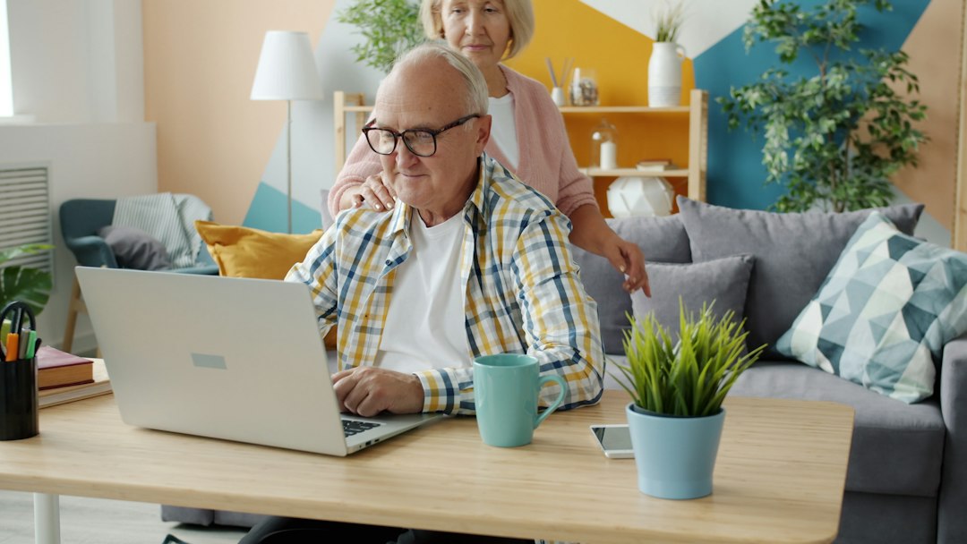 Assistance informatique à distance : couple de seniors devant leur ordinateur portable à la maison